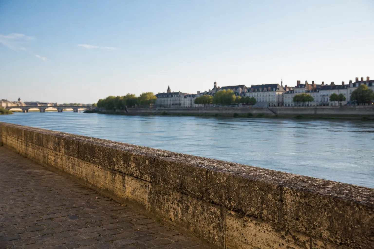 Quais de la Loire à Tours en fin d’après-midi, parapet de pierre au premier plan et toits d’ardoise au fond